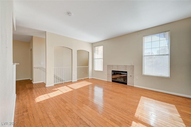 unfurnished living room featuring light hardwood / wood-style floors and a tiled fireplace