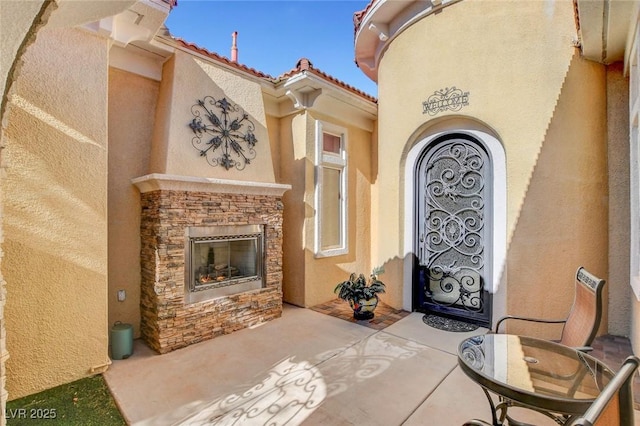 doorway to property featuring an outdoor stone fireplace and a patio area