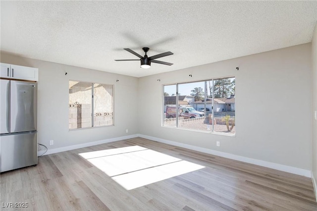 unfurnished room featuring a textured ceiling, ceiling fan, and light wood-type flooring