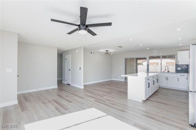 kitchen with light wood-type flooring, backsplash, white cabinetry, ceiling fan, and sink