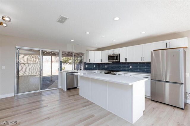 kitchen featuring light hardwood / wood-style floors, stainless steel appliances, white cabinetry, and a kitchen island