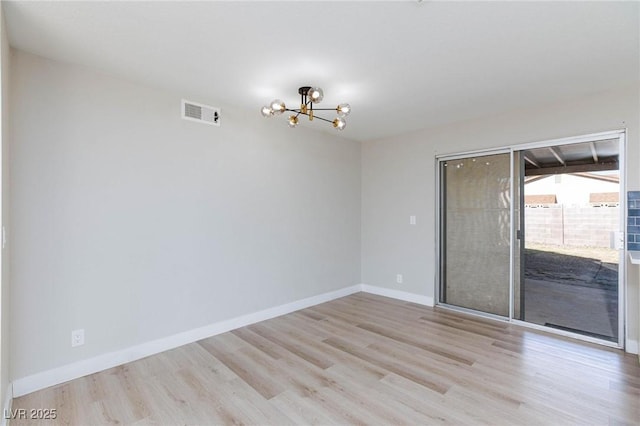 unfurnished room featuring an inviting chandelier and light hardwood / wood-style flooring