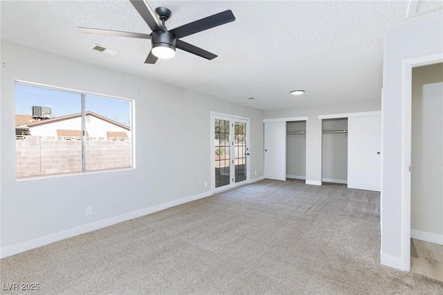 unfurnished bedroom featuring ceiling fan, light carpet, and a textured ceiling