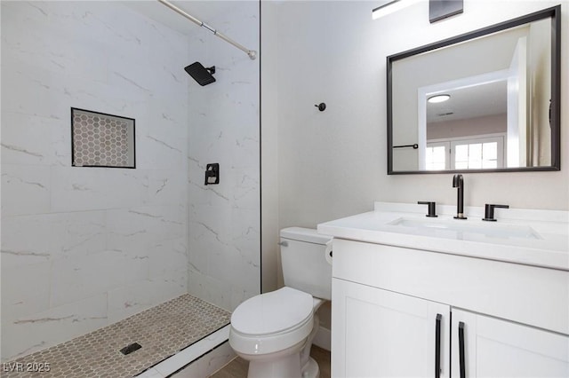 bathroom featuring toilet, vanity, and tiled shower