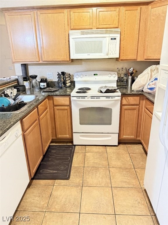 kitchen featuring sink, light tile patterned floors, dark stone counters, and white appliances