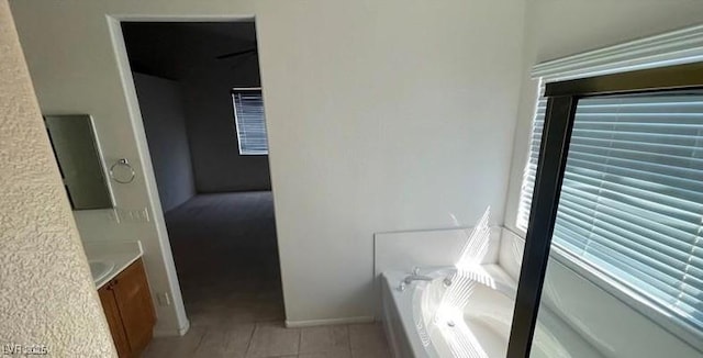 bathroom with a bathtub, vanity, and tile patterned floors