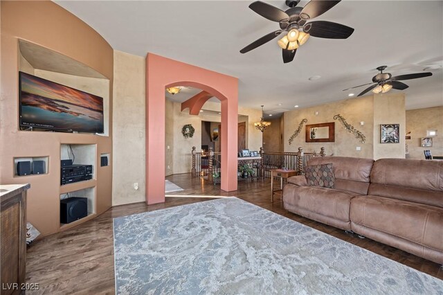 living room featuring ceiling fan with notable chandelier and dark hardwood / wood-style floors