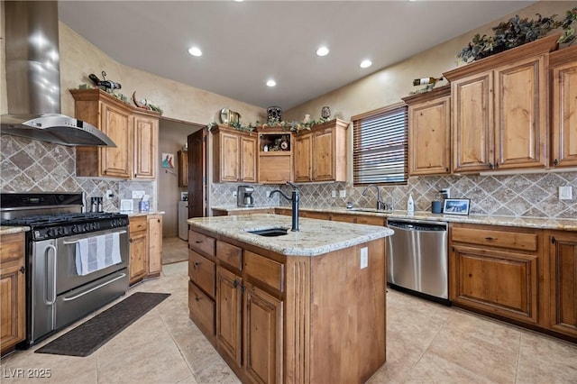 kitchen with wall chimney exhaust hood, stainless steel appliances, sink, and an island with sink