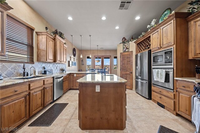 kitchen with a center island, sink, hanging light fixtures, and appliances with stainless steel finishes