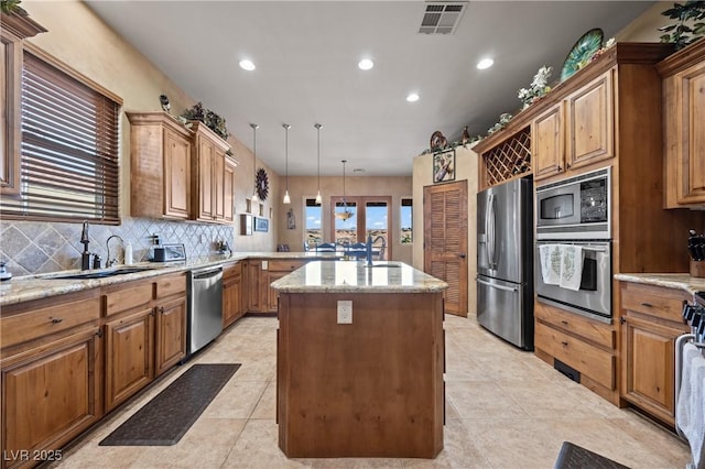 kitchen with stainless steel appliances, sink, hanging light fixtures, and a kitchen island