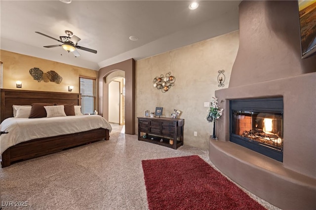 bedroom with ceiling fan and a fireplace