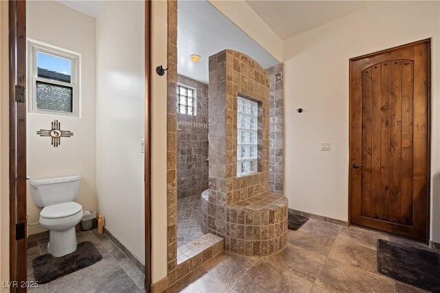 bathroom featuring a tile shower and toilet