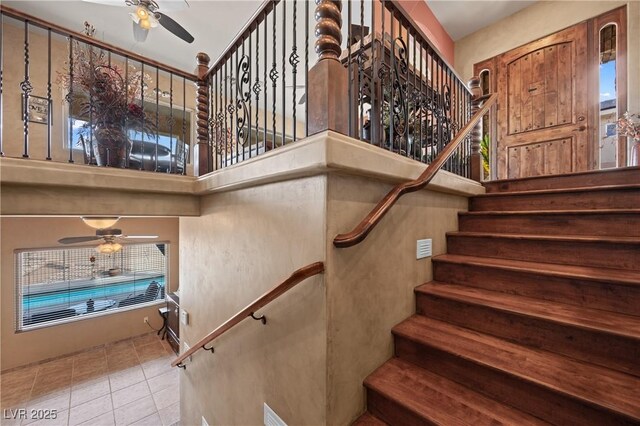 stairs featuring tile patterned floors, ceiling fan, and a high ceiling