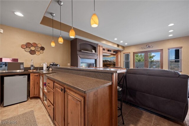 kitchen with french doors, hanging light fixtures, kitchen peninsula, a kitchen bar, and appliances with stainless steel finishes