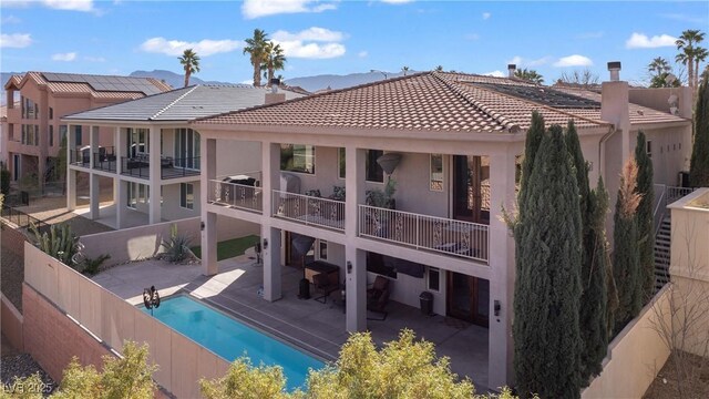 back of property featuring a patio and a fenced in pool