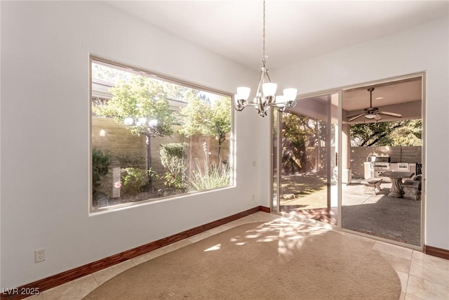 unfurnished dining area featuring light tile patterned flooring and ceiling fan with notable chandelier