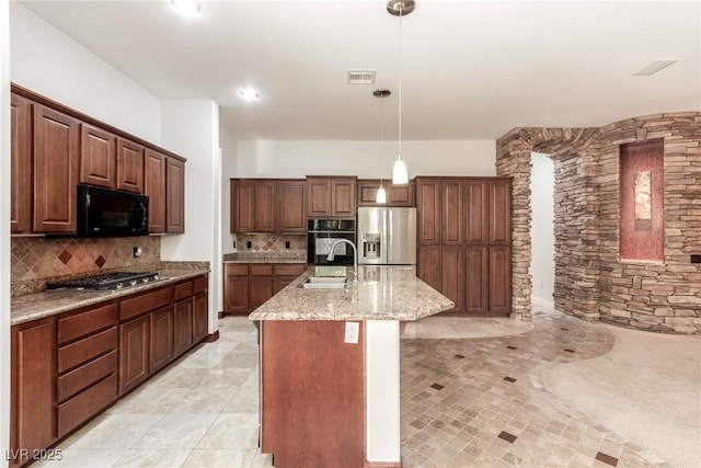 kitchen with decorative backsplash, pendant lighting, stainless steel appliances, and a kitchen island with sink