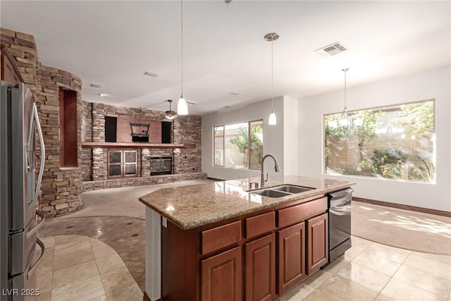 kitchen featuring light stone countertops, pendant lighting, appliances with stainless steel finishes, sink, and a kitchen island with sink