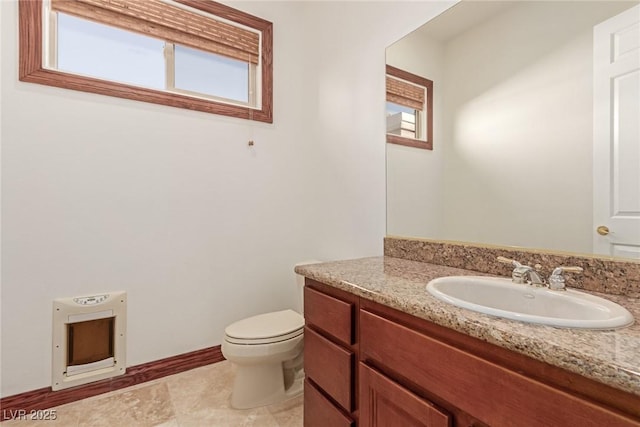 bathroom featuring toilet, heating unit, and vanity