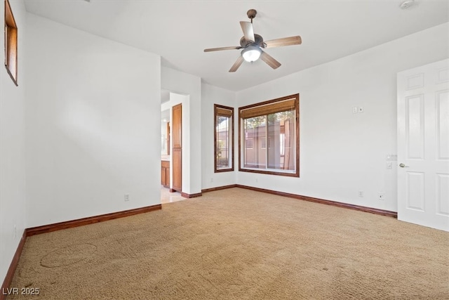 spare room featuring light carpet, ceiling fan, and baseboards