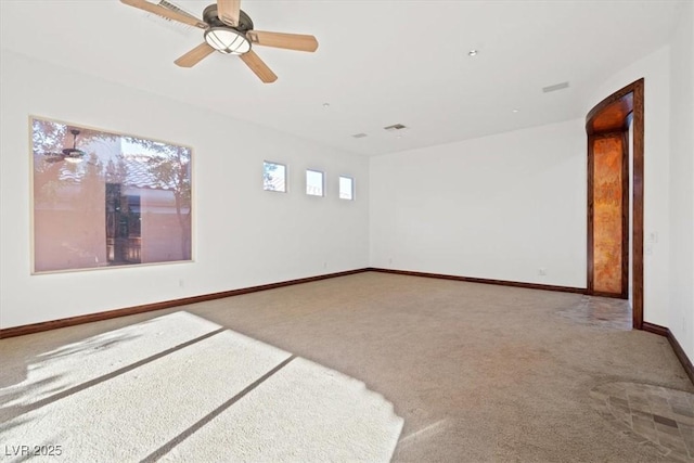 carpeted empty room with ceiling fan, visible vents, and baseboards