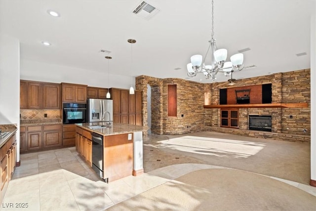 kitchen with tasteful backsplash, visible vents, a stone fireplace, black appliances, and a sink