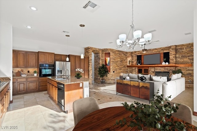 kitchen featuring brown cabinets, visible vents, a sink, a stone fireplace, and black appliances