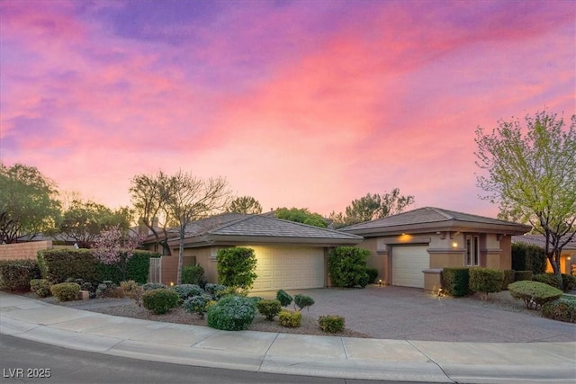 prairie-style home with a garage, driveway, and stucco siding