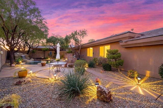 yard at dusk featuring a patio, a swimming pool, and a fenced backyard