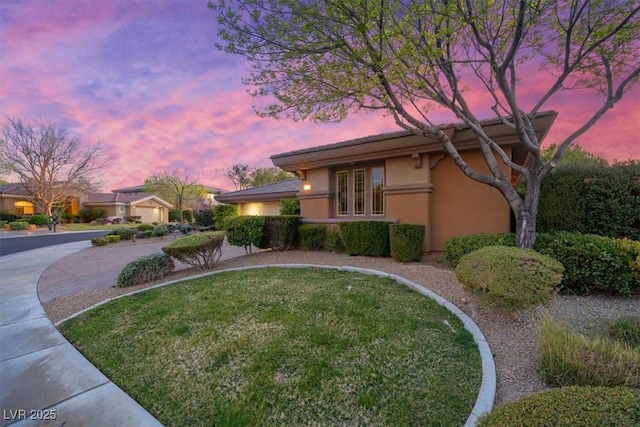 exterior space featuring driveway, a yard, and stucco siding