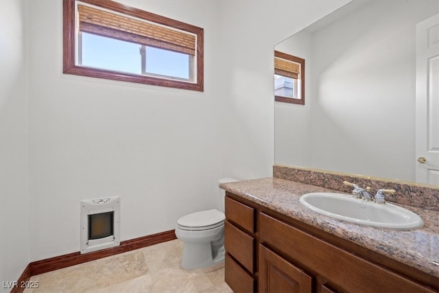 bathroom featuring baseboards, toilet, vanity, and heating unit