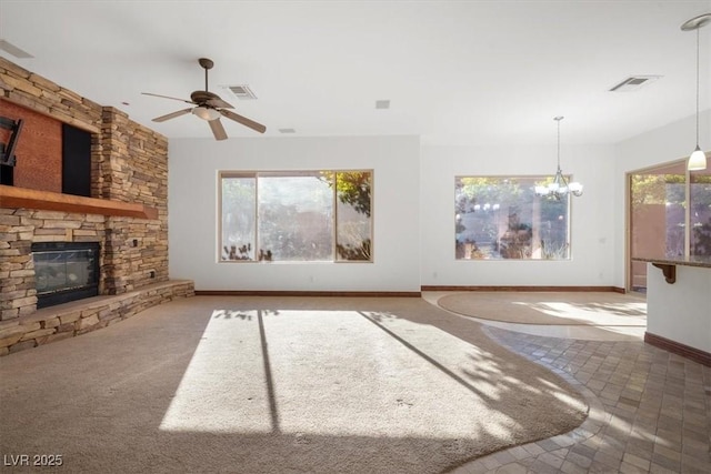 unfurnished living room with ceiling fan with notable chandelier, a fireplace, visible vents, and baseboards