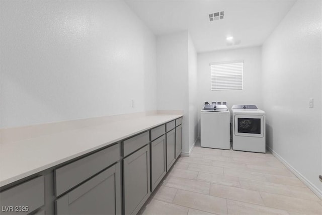 washroom with cabinets and washing machine and clothes dryer