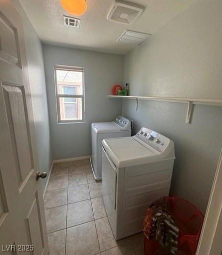 laundry room with washer and dryer, a textured ceiling, and light tile patterned flooring