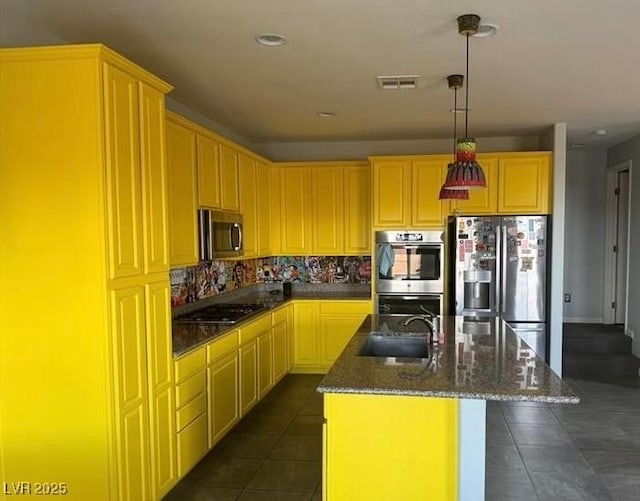 kitchen featuring dark tile patterned flooring, sink, decorative backsplash, an island with sink, and stainless steel appliances