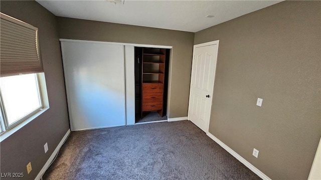 unfurnished bedroom with dark colored carpet and a closet