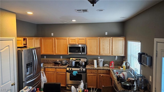 kitchen featuring dark stone counters, sink, and stainless steel appliances