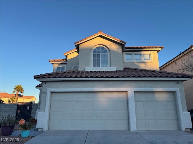 view of front of house with concrete driveway, fence, a tiled roof, and stucco siding