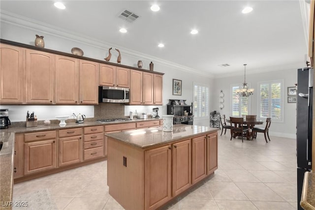 kitchen featuring hanging light fixtures, an inviting chandelier, dark stone counters, appliances with stainless steel finishes, and ornamental molding