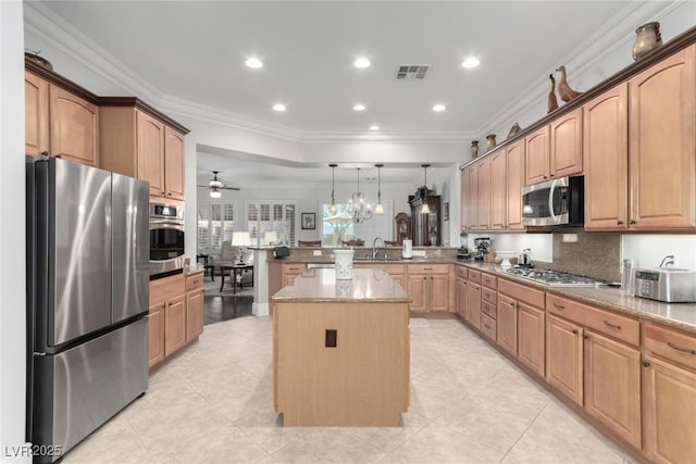 kitchen with light stone counters, stainless steel appliances, ceiling fan, pendant lighting, and a kitchen island