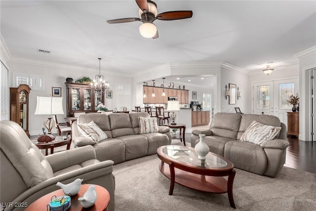 carpeted living room featuring crown molding, french doors, and ceiling fan with notable chandelier