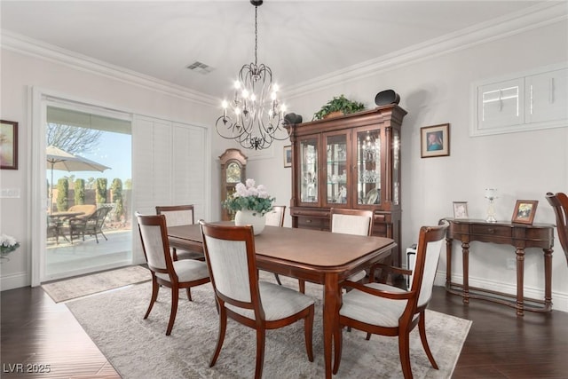 dining room with dark hardwood / wood-style floors, ornamental molding, and a notable chandelier