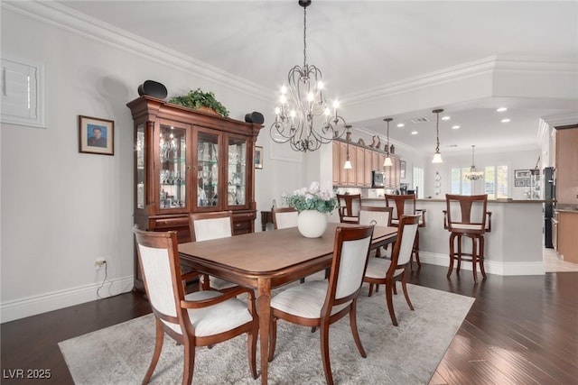 dining space with dark wood-type flooring, an inviting chandelier, and ornamental molding