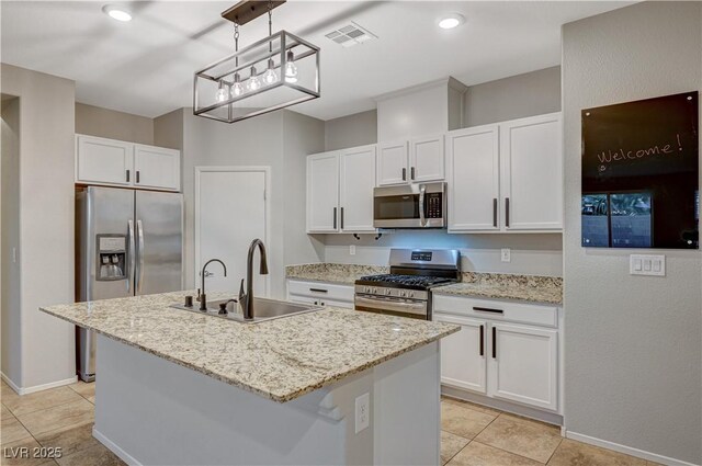 kitchen featuring stainless steel appliances, sink, pendant lighting, white cabinets, and an island with sink