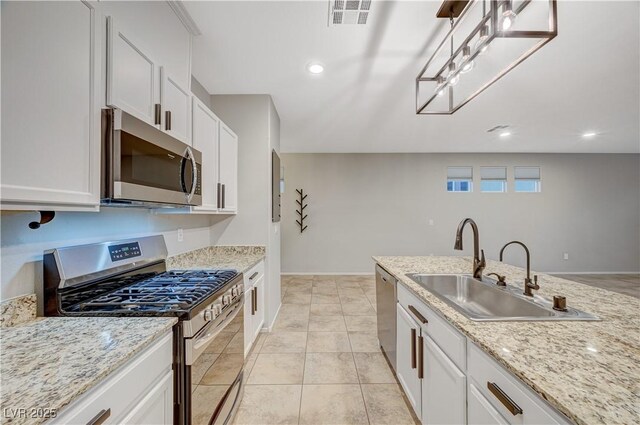 kitchen featuring white cabinets, sink, light tile patterned floors, light stone countertops, and appliances with stainless steel finishes