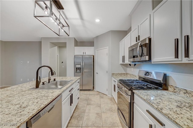 kitchen with appliances with stainless steel finishes, sink, pendant lighting, white cabinets, and light tile patterned flooring