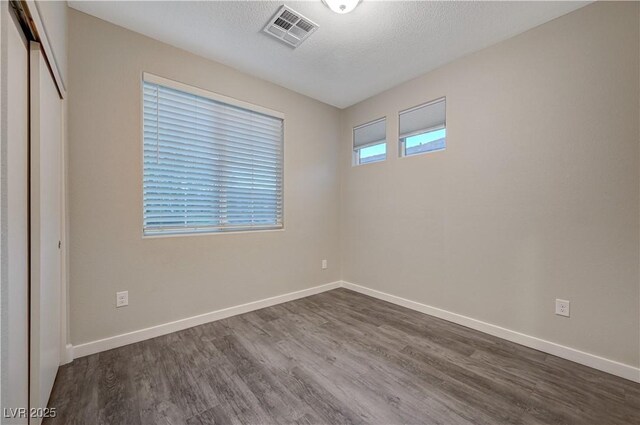 unfurnished room featuring dark hardwood / wood-style flooring and a textured ceiling