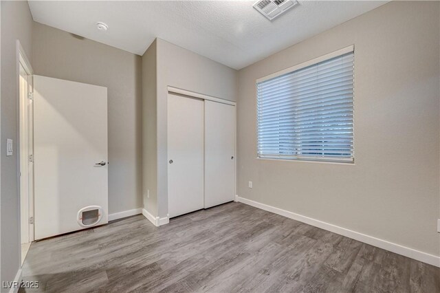 unfurnished bedroom featuring a closet, a textured ceiling, and light wood-type flooring