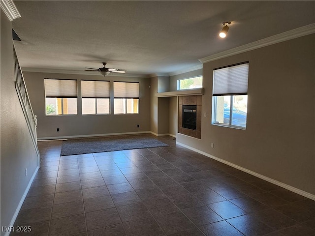 unfurnished living room with ceiling fan, a tile fireplace, and crown molding