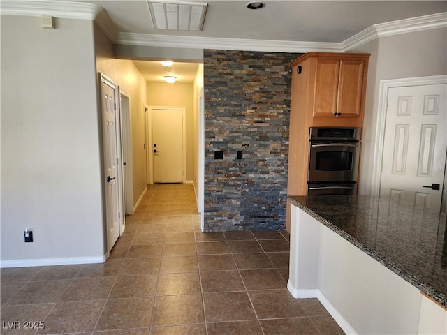 kitchen with dark tile patterned floors, stainless steel double oven, dark stone countertops, and crown molding